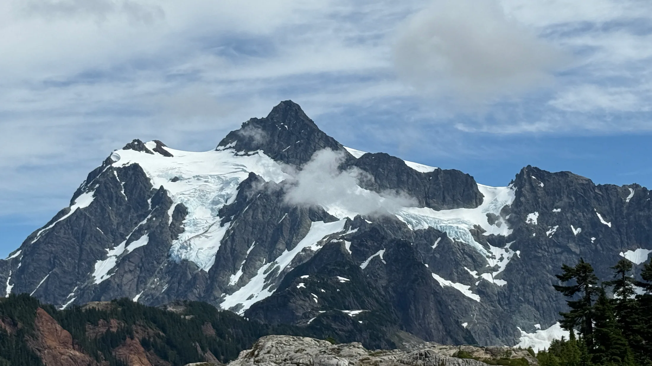山峰近景，冰川和岩壁之间仍飘着云