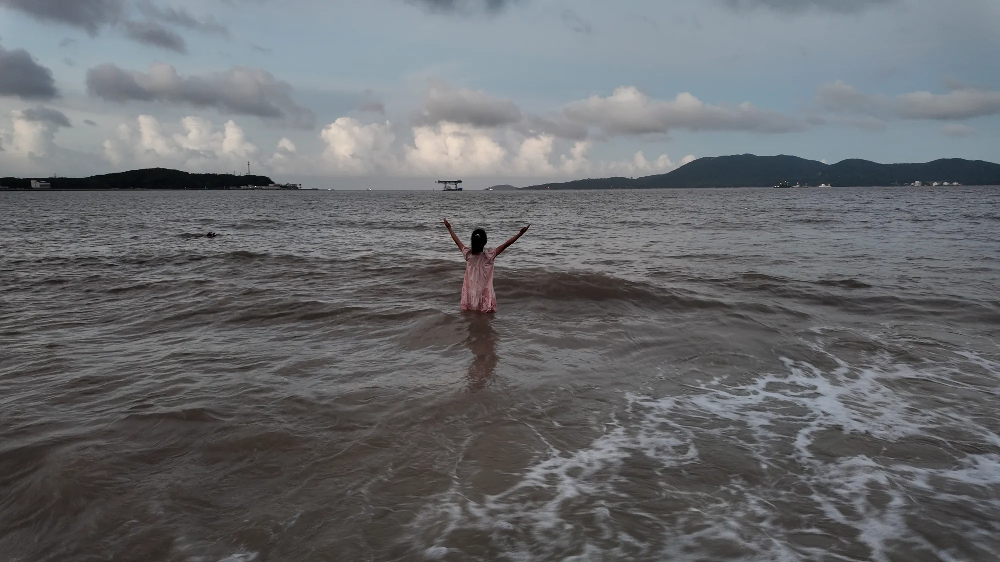 妹妹站在舟山海边，海浪漫过脚边