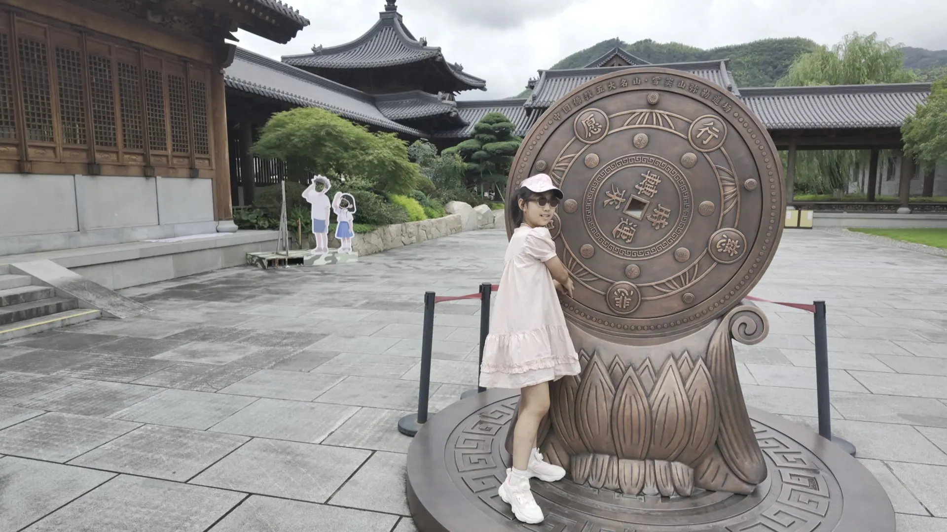 女儿站在雪窦寺庭院的铜鼓旁