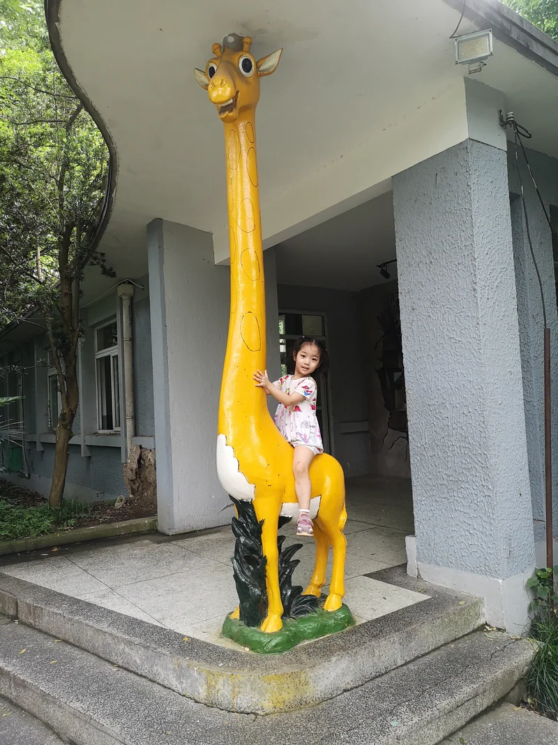 2020年,小时候的妹妹坐在黄色长颈鹿雕像上,双手扶着长脖子