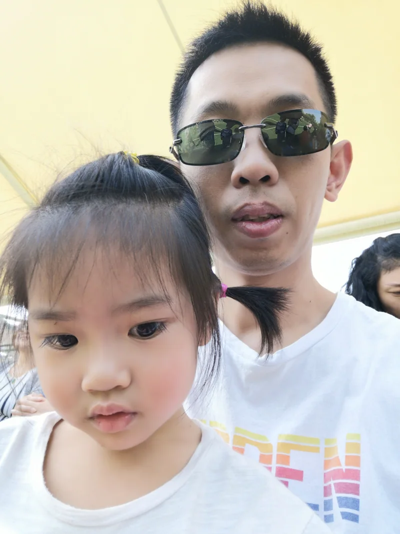 2019年,戴墨镜的爸爸与梳着小辫子的妹妹合影