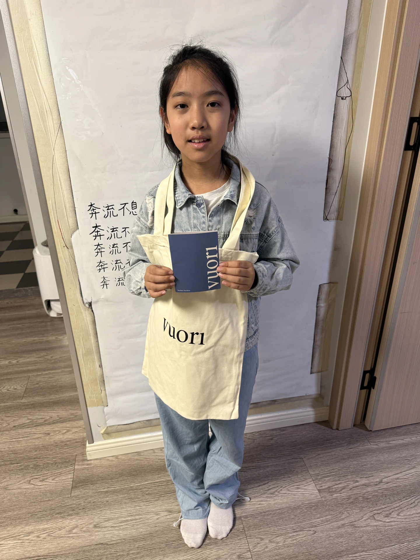 妹妹背着换到的 Vuori 帆布包,手里拿着小册子